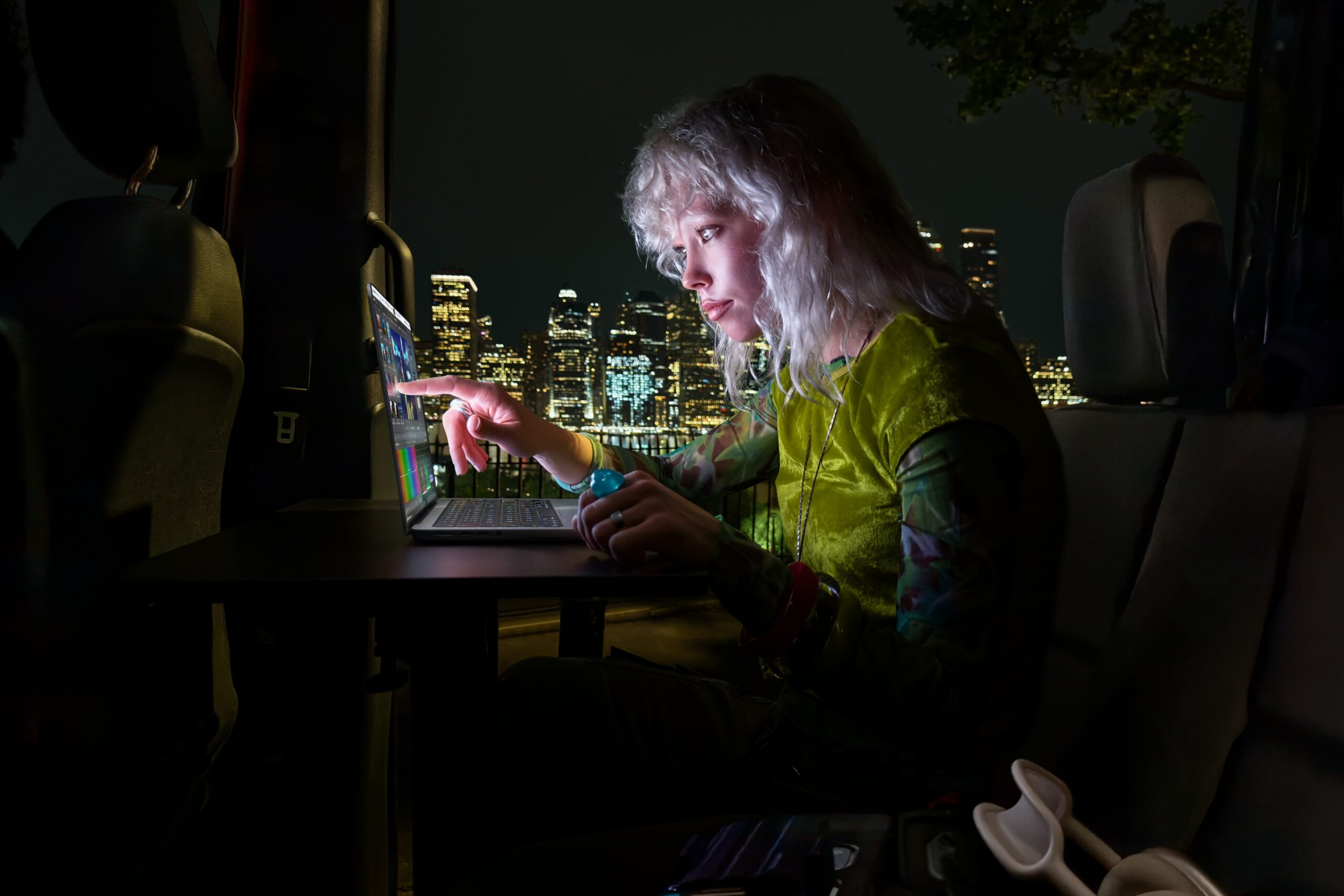 使用者在夜間行動工作情境觸控 MacBook Pro 影片編輯介面